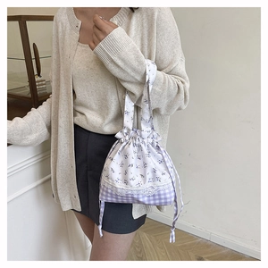 Detailed shot of floral and plaid drawstring tote bag with delicate lace edge trim