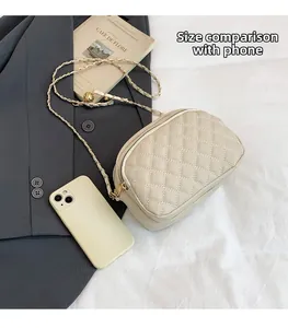 Close-up of a quilted cream crossbody bag showing texture and size comparison with a phone