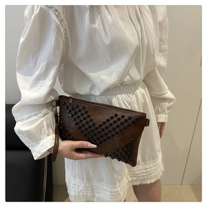 Close-up of brown clutch bag with black rivet geometric pattern and zipper detail
