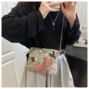 Detailed close-up of sequined embroidery featuring multi-colored leaf patterns and metal chain