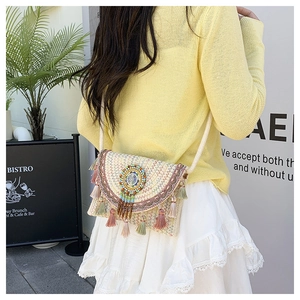 Detail of bohemian woven bag featuring colorful tassel fringe and ethnic bead pendant