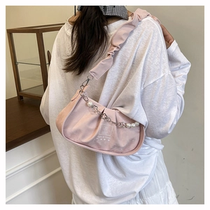 Détail du sac baguette rose plissé avec chaîne en perles et logo sur l'épaule