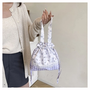 Detail of floral and checkered drawstring bucket bag with delicate lace trim