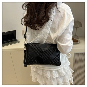 Detail of black envelope crossbody bag with geometric rivet studs in a lifestyle setting