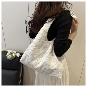 Close-up of white canvas tote bag with delicate yellow flower embroidery and lace details