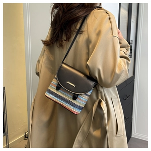 Detail of multi-color woven crossbody bag featuring a black leather flap with gold logo