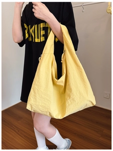 Macro detail of large yellow tote bag featuring crinkled nylon fabric and side zipper