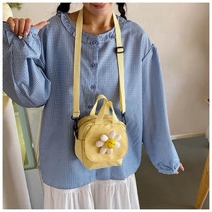 Détail du sac en toile jaune avec marguerite 3D et motif de visage souriant