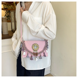 Detail of pink straw crossbody bag with boho tassels and mandala bead decoration