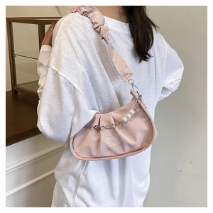 Détail du sac à bandoulière plissé rose avec chaîne de perles et breloques à fleurs
