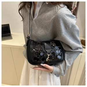 Detailed view of black sequin shoulder bag with leather trim and gold metal buckle