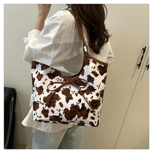 Borsa tote con stampa mucca e fiocco indossata da una modella che ne mostra la capienza