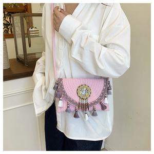 Detailed shot of pink woven crossbody bag featuring colorful tassels and beadwork details
