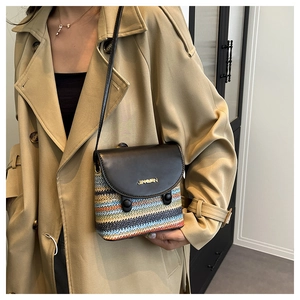 Détail de la texture en paille tressée colorée avec rabat en cuir noir et logo doré du sac bandoulière