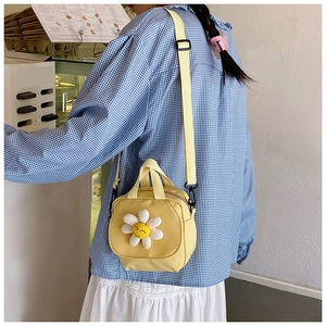 Gros plan d'un mini sac en toile jaune avec applique marguerite et broderie sourire