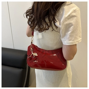 Detail of red patent leather hobo bag featuring a cherry charm and zipper closure