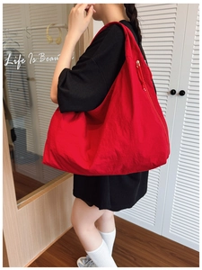 Detailed shot of large capacity red hobo bag with pleated texture on model
