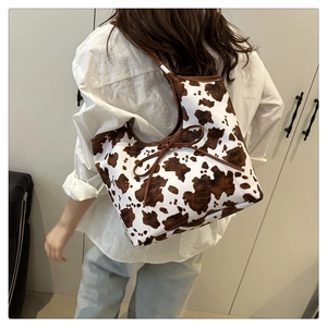 Dettaglio della borsa con stampa mucca, fiocco marrone e tracolla dal design retrò