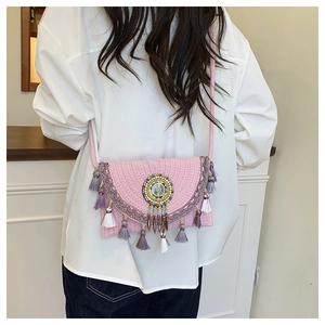 Detail of pink woven crossbody bag featuring bohemian fringe and beaded embellishments