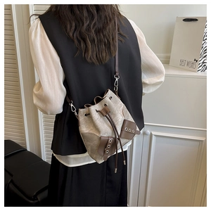 Canvas bucket bag detail with drawstring closure and brown leather trim on model