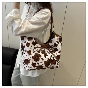 Detail of cow print tote bag with brown ribbon bow and slim shoulder straps on model