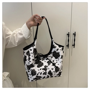 Dettaglio della borsa tote con stampa mucca, fiocco nero e trama in ecopelle