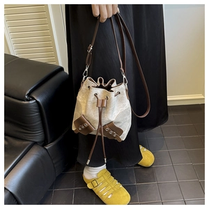 Detail of canvas bucket bag with leather trim and drawstring closure on a model