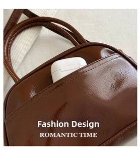 Detail einer braunen Handtasche aus Glanzleder mit Seitentasche und Kopfhöreretui innen