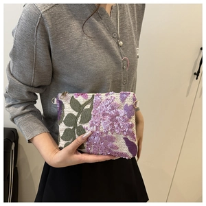Detail of floral embroidery and purple sequins on an elegant evening clutch bag