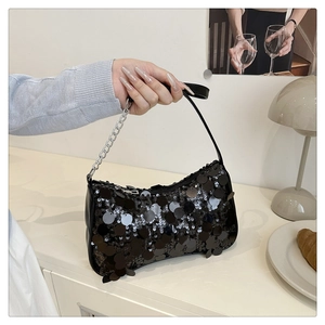 Close-up of black sequined handbag with decorative silver chain and leather shoulder strap