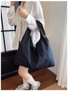 Detail of black large capacity tote bag with zipper closure and smooth nylon texture