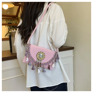 Detail of pink woven bohemian crossbody bag with colorful beads and long fringe tassels