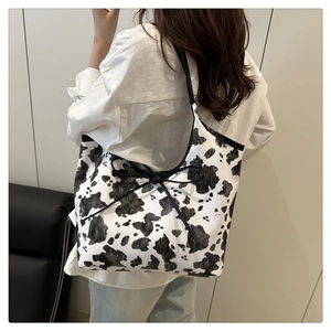 Dettaglio della borsa tote con stampa muccata, fiocco nero decorativo e manici lunghi