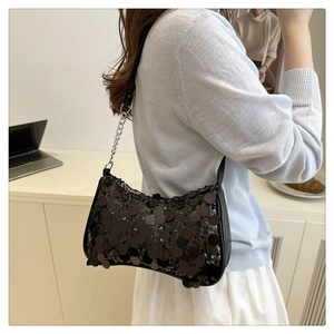 Close-up of black sequined underarm bag with silver chain strap shown on a model