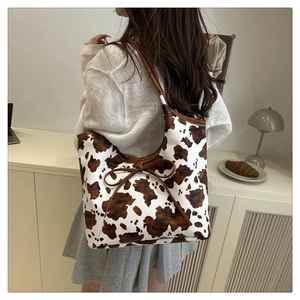Dettaglio di una borsa tote con stampa mucca marrone, piccolo fiocco e trama in pelle di qualità