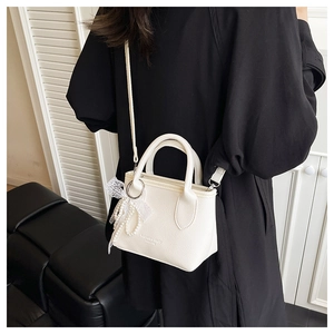 Close-up of a white pebbled leather bucket bag with elegant pearl and lace charm detail