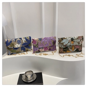 Tre pochette da sera ricamate con paillettes e catene dorate su moderno display bianco