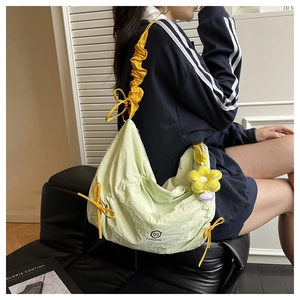 Dettaglio della borsa a pieghe verde chiaro con fiocco giallo e ciondolo a girasole