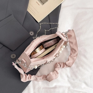 Sac nuage rose froncé avec chaîne en perles et maquillage vu du dessus
