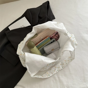 White floral canvas tote bag with large capacity showing daily essentials in top view
