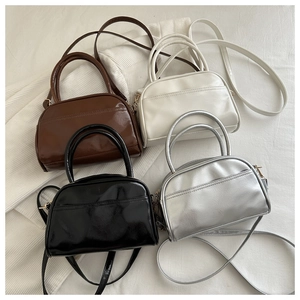 Close-up of stylish glossy pillow bags in black, brown, white, and silver finishes