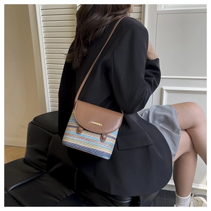 Detail of colorful woven shoulder bag with brown leather flap and golden logo buckle