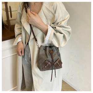 Close-up of a smoke gray drawstring bucket bag with leather accents on a model