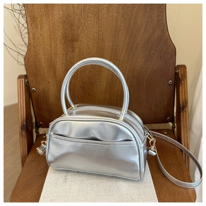 Detailed view of a silver metallic pillow bag on a chair showing the texture and handles
