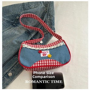 Detailed view of denim underarm bag with red gingham trim and cherry embroidery