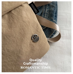 High-quality close-up detail of a minimalist khaki canvas crossbody bag with tag