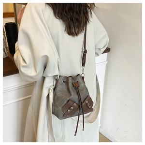 Detailed view of canvas bucket bag with drawstring closure and brown leather拼接 trim