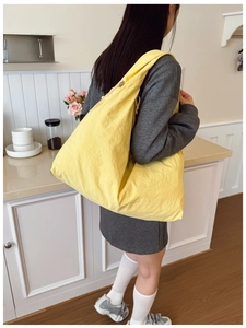 Rear view of model wearing a large bright yellow nylon tote bag in a cozy home setting