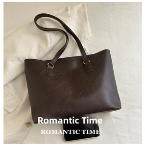 Detailed view of coffee brown tote bag with pebble leather texture and metal buckles