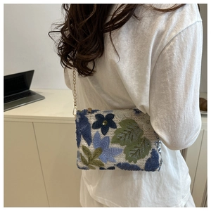 Detail of floral sequin embroidery and gold chain strap on a stylish crossbody bag